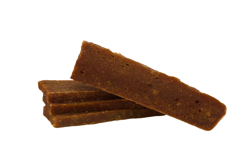 Three brown dog treats stacked on a gray background